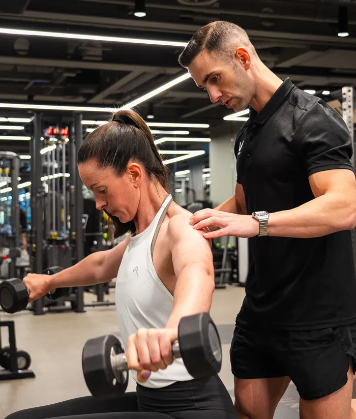 Maurizio coaching a client through a dumbbell exercise